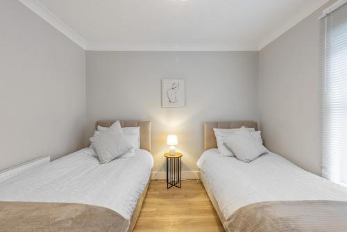 two twin beds in a room with a lamp at 12 osbourne road in Gillingham