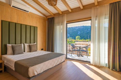 a bedroom with a bed and a large window at Perast Garden Hotel in Cıralı