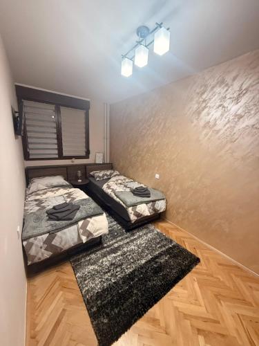 two beds in a room with wooden floors at Gohemi Apartments in Pirot