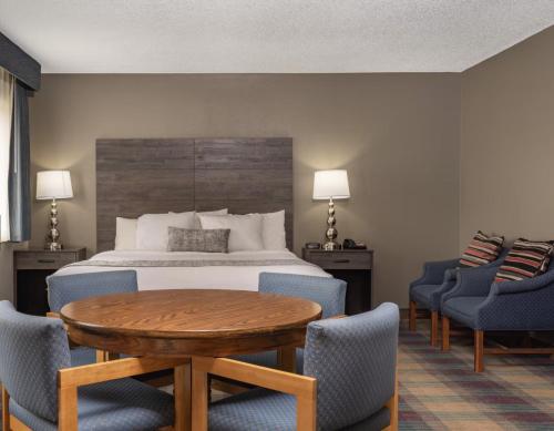 a hotel room with a bed and a table and chairs at Baymont by Wyndham Baldwin in Baldwin