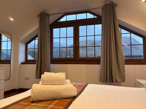 a bedroom with a bed with two pillows and windows at Sheraton Apartments in Fort William