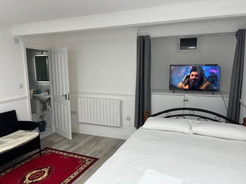 a bedroom with a bed with a tv on the wall at 525 Romford Rd, Fabulous Room in London