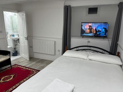 a bedroom with a white bed with a tv on the wall at 525 Romford Rd, Fabulous Room in London