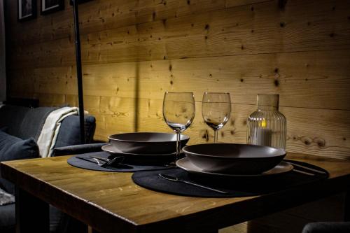 een houten tafel met twee wijnglazen en borden erop bij Le lodge étoilé in Égat