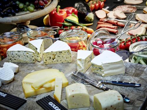a table filled with cheese and vegetables and other foods at 25hours Hotel The Royal Bavarian in Munich