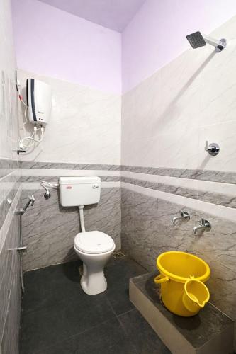 a bathroom with a toilet and a yellow bucket at Dream Garden Homestay in Madikeri