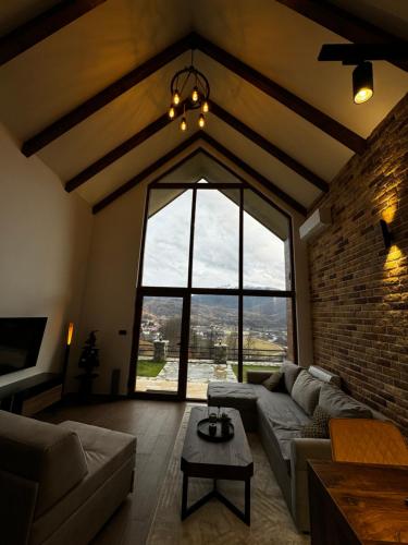 een woonkamer met een bank en een groot raam bij Monte Rustic Chalets in Mojkovac