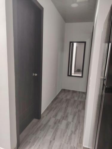 a hallway with a black door and a mirror at NaGLo1527 in Estación El Salto