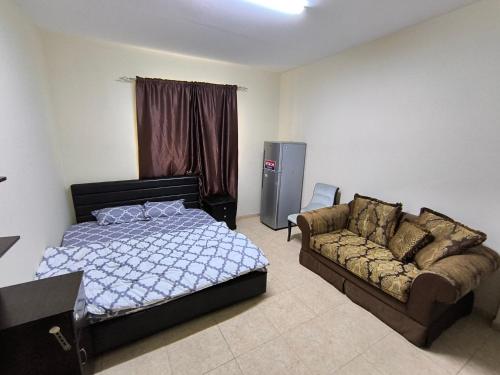 a bedroom with a bed and a couch at Rooms for family near to bus station in Ajman