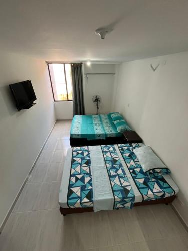 two beds in a small room with a window at Apartamento Completo in Cartago