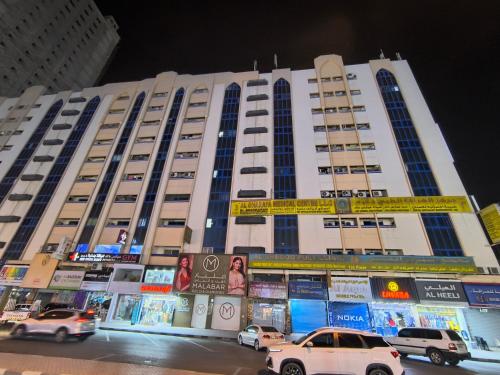 a large building with cars parked in front of it at Rooms for family near to bus station in Ajman