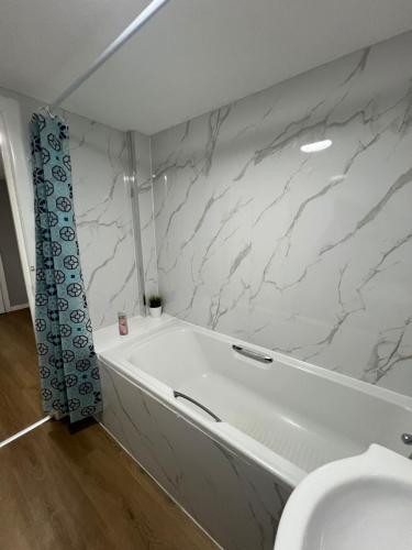a bathroom with a white tub and marble walls at Cosy Retreat Suites in Hamilton