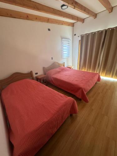 a room with two beds with red sheets and a wooden floor at Alaska cabin in Choroico