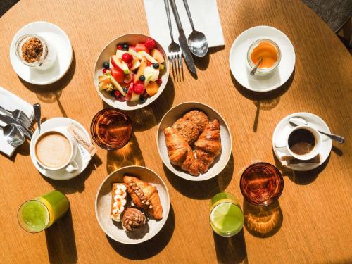 een houten tafel met daarop borden met eten en drinken bij Mondrian Ibiza in Cala Llonga