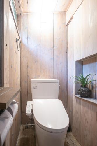 a bathroom with a white toilet and wooden walls at Lucia Seaside Villa Amami in Amami