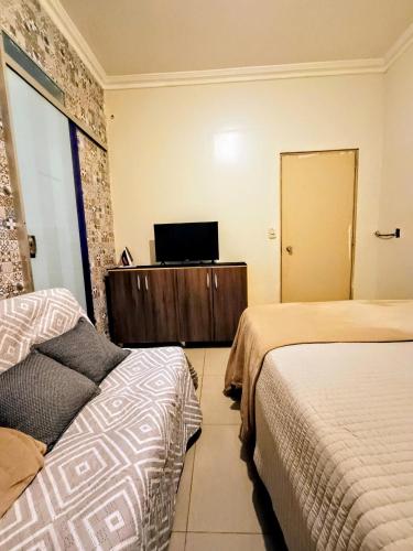 a hotel room with two beds and a television at Apto inteiro 3 quartos, sendo duas suítes in Belém