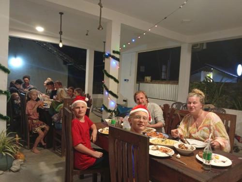 a group of people sitting at a table eating food at Kusuma's Lazy Left hostel in Midigama