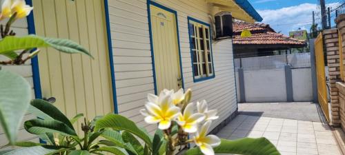 een geel huis met een gele deur en bloemen bij Pousada MALIBU BEACH in Florianópolis