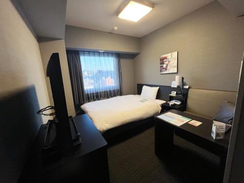 a small hotel room with a bed and a table at Hotel Route Inn Kasai Hojonoshuku in Kasai
