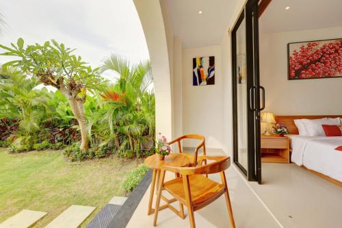 ein Schlafzimmer mit einem Bett, einem Tisch und einem Stuhl in der Unterkunft Close to Beach Paddy View 6BR Villa with Billiard in Tanah Lot