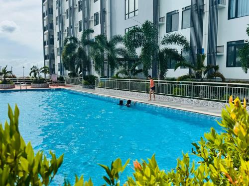 un uomo e due cani in una piscina di fronte agli edifici di ARC Towers Condominium a Cebu City