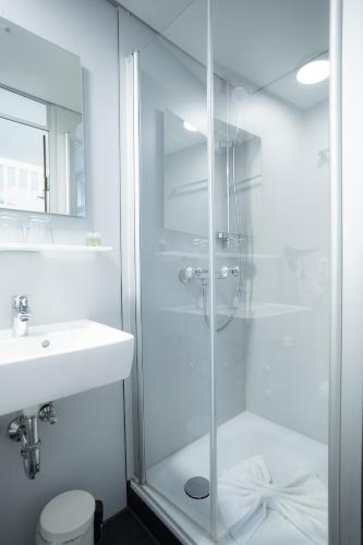 a white bathroom with a shower and a sink at Heimatgleis in Brilon-Wald