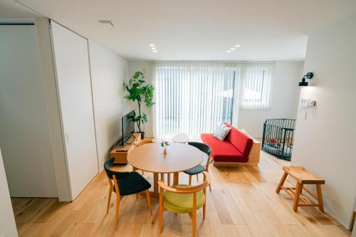 a living room with a table and chairs and a red couch at 藤乃宿 Villa Moere モエレ沼公園すぐ 愛犬と一緒に泊まれる新築1棟貸し in Sapporo