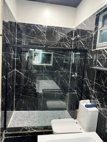 La salle de bains est pourvue de carrelage noir, de toilettes et d'une douche. dans l'établissement Elegant 1-Bedroom Retreat, à Miami