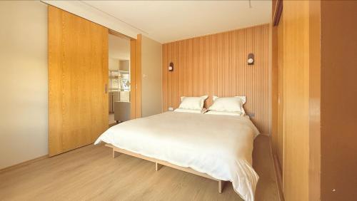 una camera da letto con un letto con lenzuola bianche e pareti in legno di 涼亭 川 Ryoutei Kawa a Hakuba