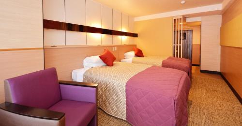 a hotel room with two beds and a chair at Heian No Mori Kyoto in Kyoto