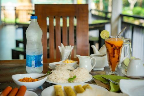 een tafel met borden eten en drinken bij Evergreen Villa - Sinharaja in Deniyaya