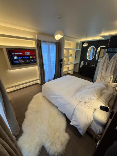 a bedroom with a large white bed and a tv at L'Écrin Beige - Immersive suite with private Jacuzzi in Champlan