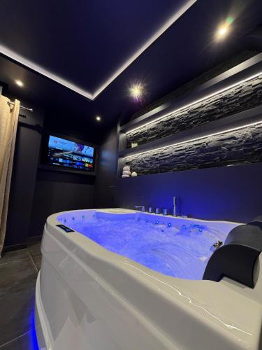 a bath tub in a room with a tv at L'Écrin Beige - Immersive suite with private Jacuzzi in Champlan