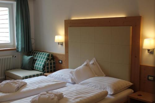a hotel room with two beds and a chair at Christophorus Mountain Residence in San Vigilio Di Marebbe