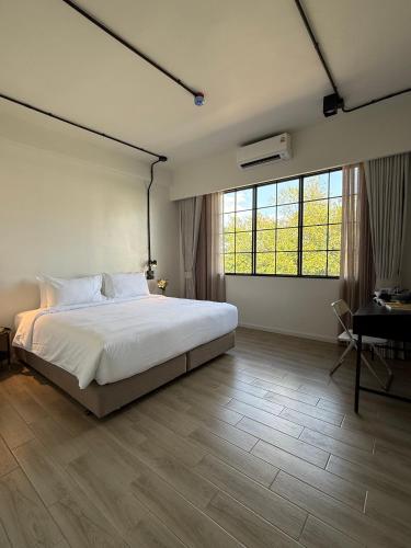 a bedroom with a large white bed and a desk at Holmes Pranakorn in Bangkok