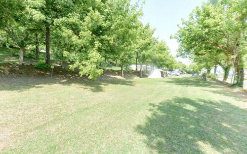 a large grass field with trees on the side of it at Camping Village Mar y Sierra in San Costanzo