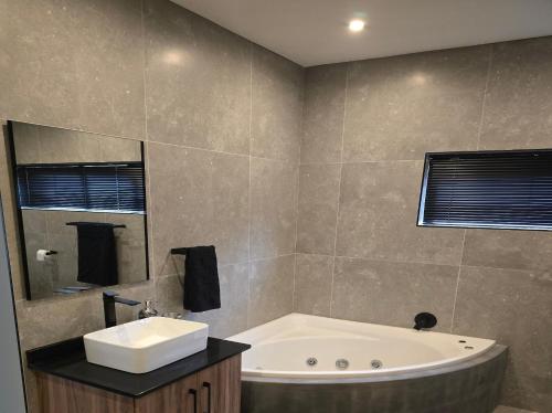 a bathroom with a tub and a sink and a mirror at Crane's Nest - Luxury Ground in Pretoria