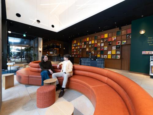 two people sitting on a couch in a lobby at Tokyu Stay Hakata in Fukuoka