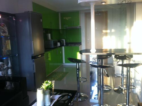 a kitchen with green cabinets and bar stools at Sea Residences MOA-Eric Apartments in Manila