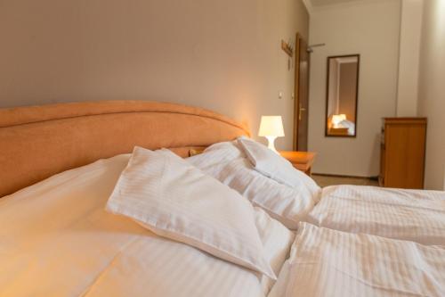 a bed with white sheets and pillows on it at Hotel Grand in Žilina