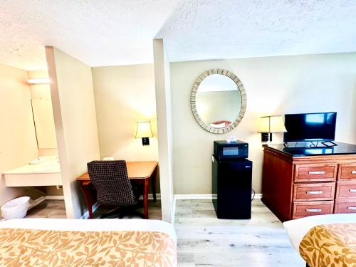 een hotelkamer met een bed, een bureau en een spiegel bij Rodeway Inn Jackson Northwest in Jackson