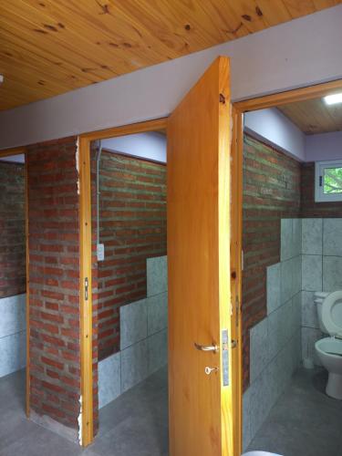 een badkamer met een toilet en een bakstenen muur bij Hostel El Duende Errante in El Bolsón