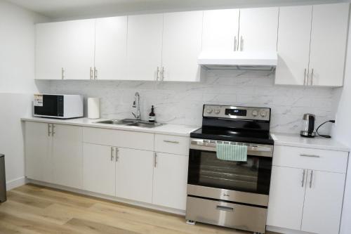 een keuken met witte kasten en een kookplaat oven bij Sunny Suite in Saskatoon