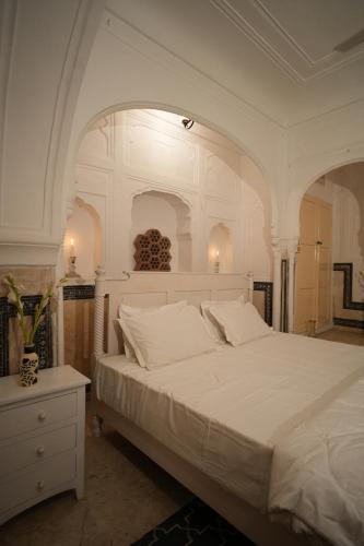 a bedroom with a large white bed with an archway at Bagru Haveli in Jaipur