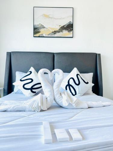 een bed met witte lakens en kussens in de vorm van hartjes bij เดอะซันเซ็ท บางแสน Exclusive Top Floor in Chon Buri
