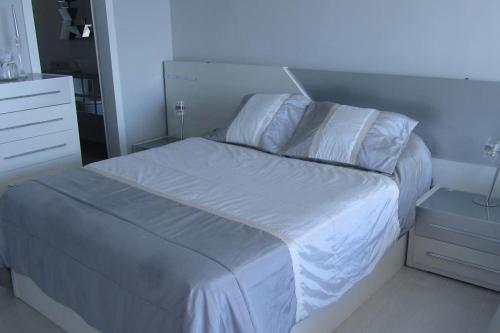 Una cama con sábanas blancas y almohadas en un dormitorio en Carpe Diem en San Agustín