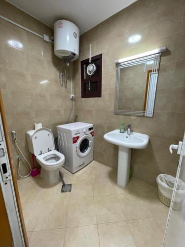 a bathroom with a washing machine next to a toilet and a sink at Furnished 2BR Central Al Ain in Al Ain