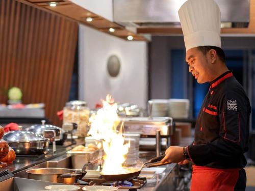ein Koch, der Essen in einer Küche mit Flammen zubereitet in der Unterkunft Novotel Palembang in Palembang