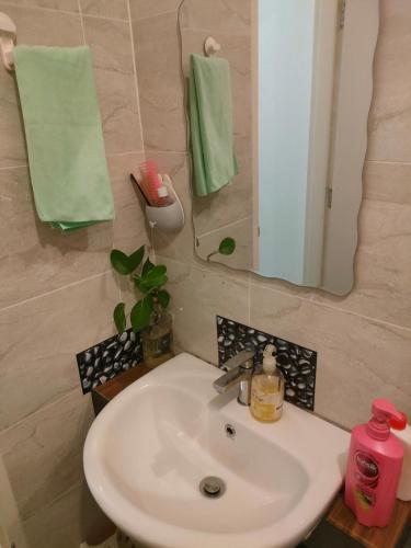 a bathroom sink with a mirror and green towels at SKS Pavillion Residences - High Floor with Singapore View in Johor Bahru