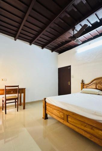 a bedroom with a wooden bed and a desk at HARSHAM Eco Village in Puthuppādi